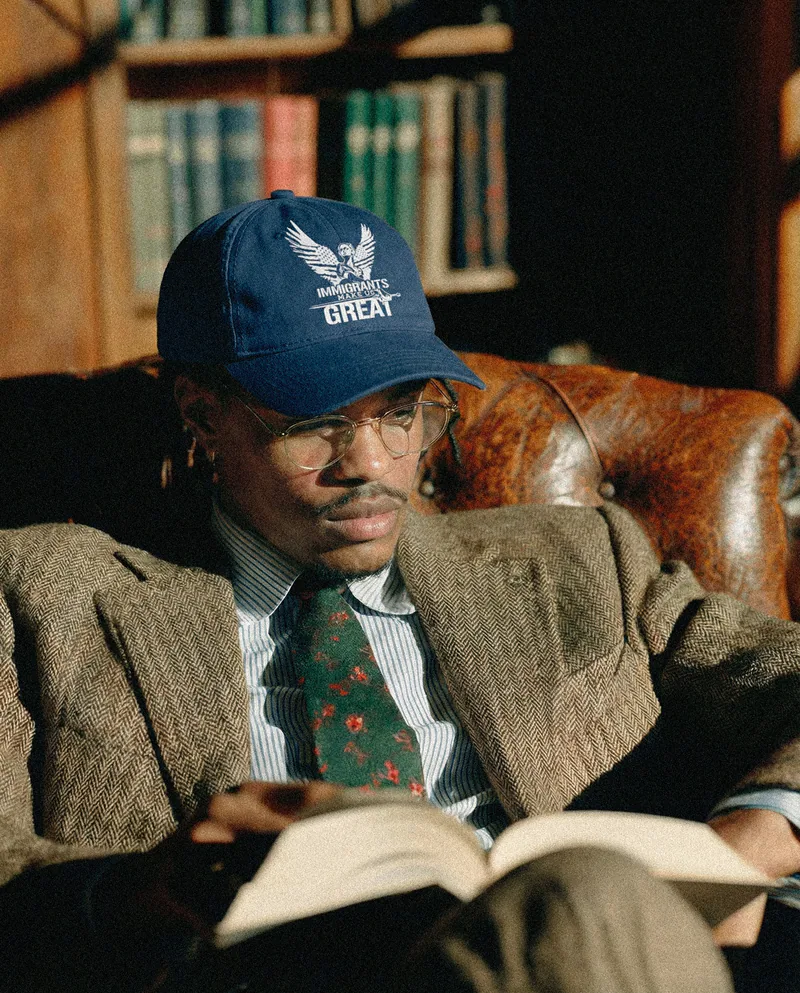 A reader in the Legacy Cap and tailored tweed, seated with a book in a panelled library